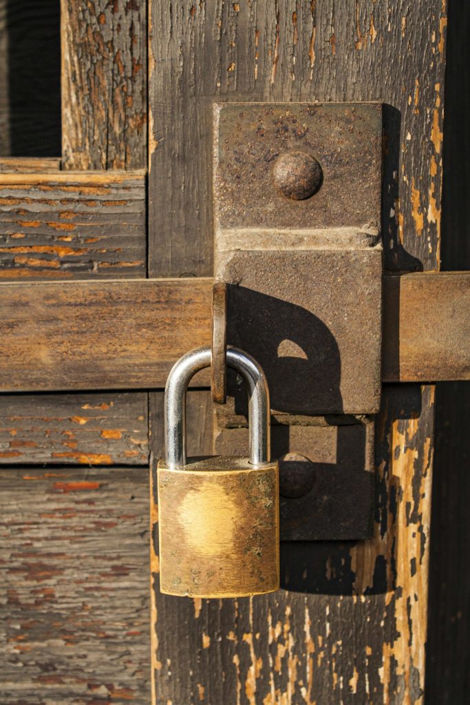 Brass padlock securing an old wooden door