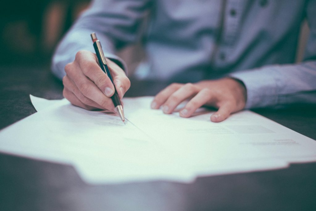 Person reviewing and signing a paper document with a pen