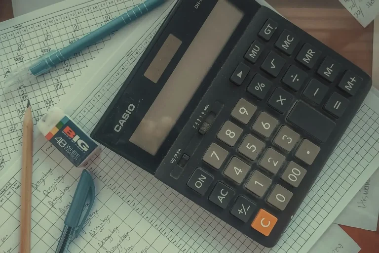 A calculator on tax worksheets with pens