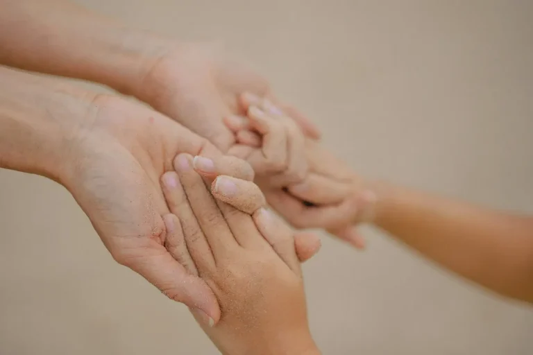 An adult gently holding a child's hand