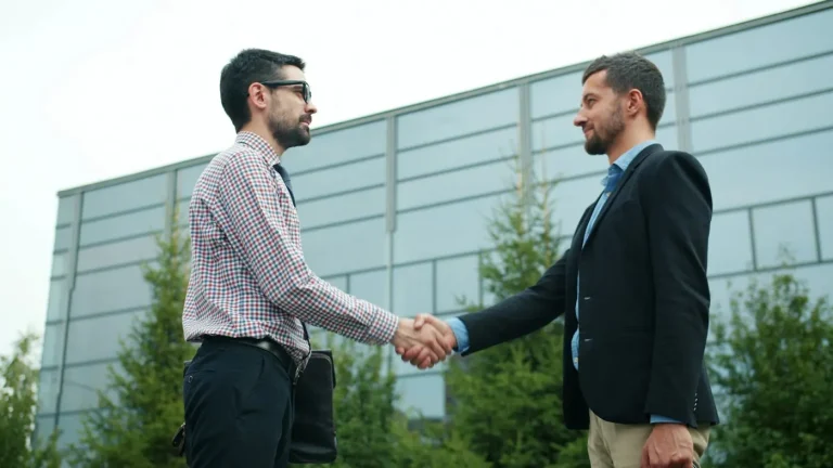 Two business people shaking hands outside a modern building