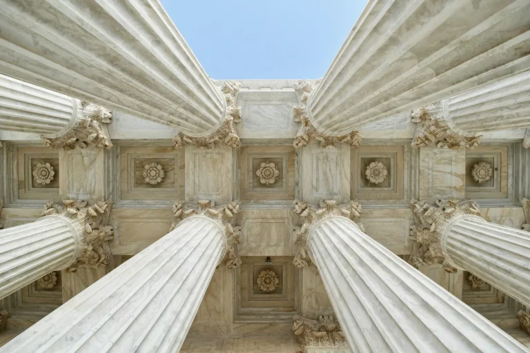Looking up at white marble columns of a courthouse