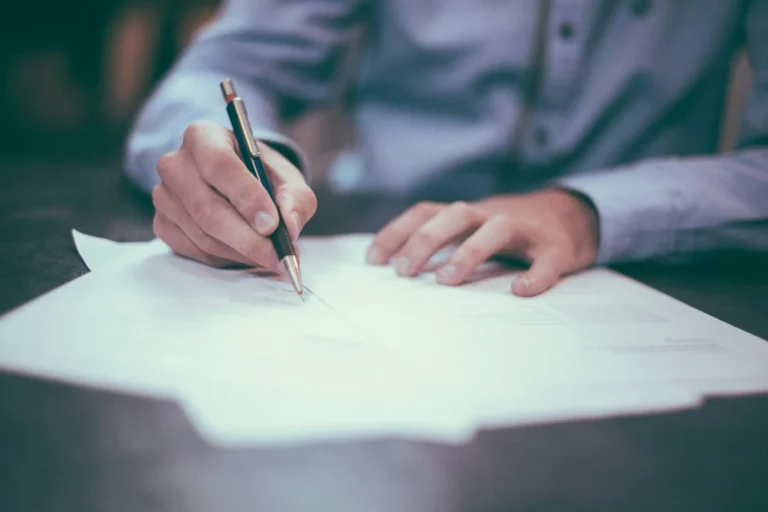 Person reviewing and signing a paper document with a pen